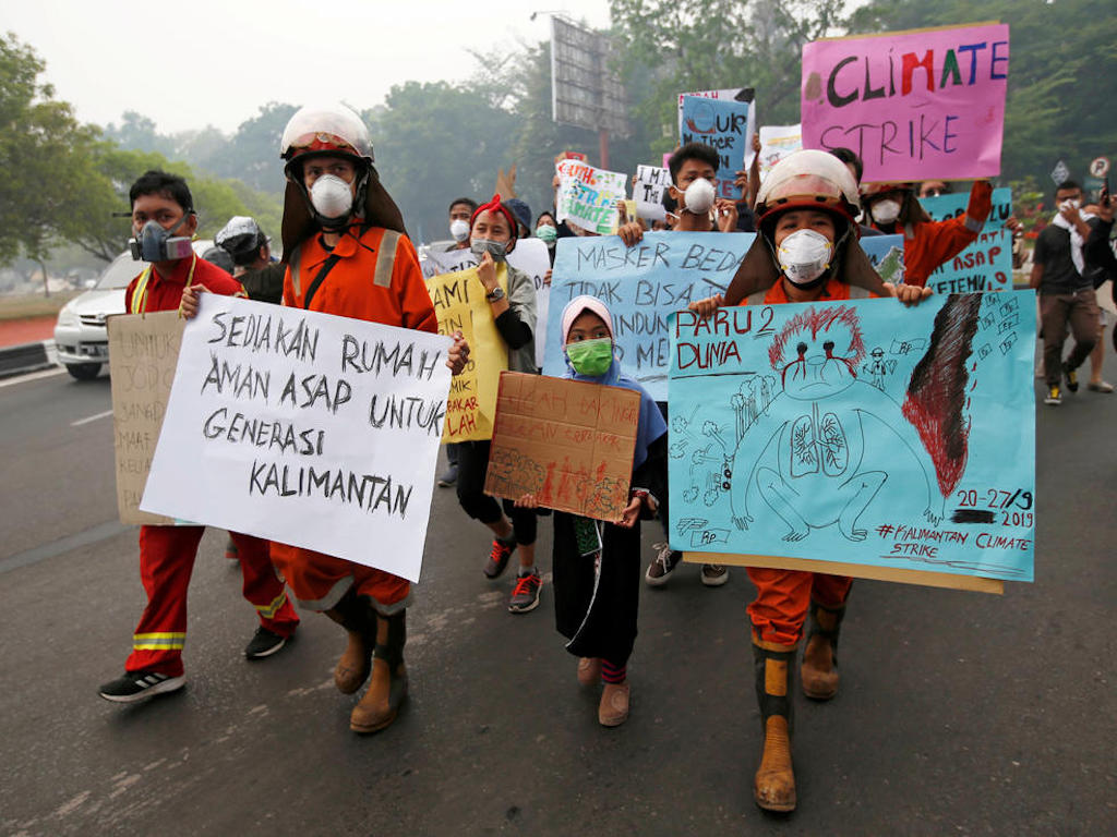 Youths walk with placards through the main road during a Global Climate Strike rally as smog covers the city due to the forest fires in Palangka Raya - Green Queen Media Covering Climate Now
