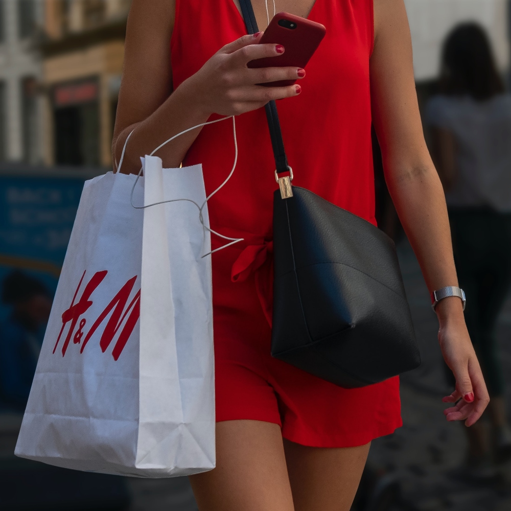 a woman walks with an H&M bag