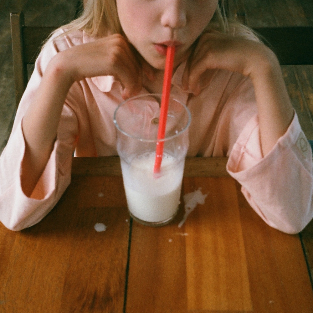 a young girl drinking milk through a straw